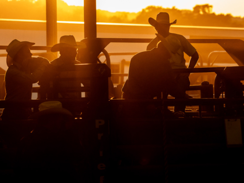The sun sets behind a group of cowboys on the chutes at the rodeo in Dripping Springs, Texas, July 26th, 2019.
