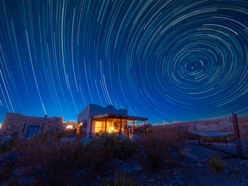 Star trails over a desert cabin.